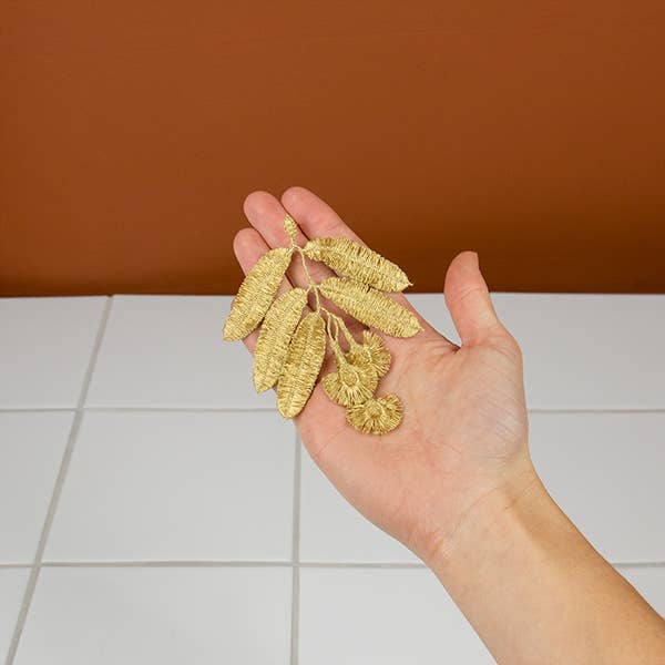 The Botanopia Eucalyptus flowers embroidery brooch held in a hand.