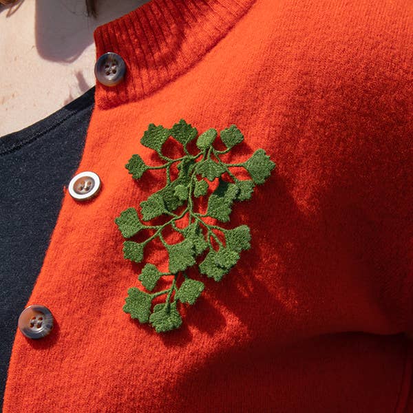 A person wearing the Botanopia Maidenhair fern embroidery brooch on a red cardigan.