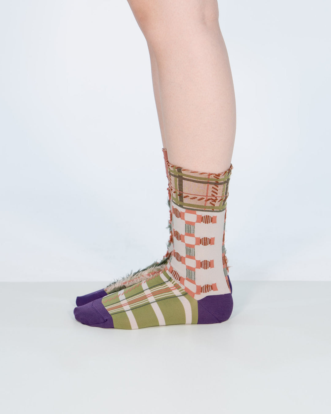 A model wearing Atelier Textiles Pink socks in green, purple, and orange on her legs, made in Japan, showcasing different ways to wear them against a white background.