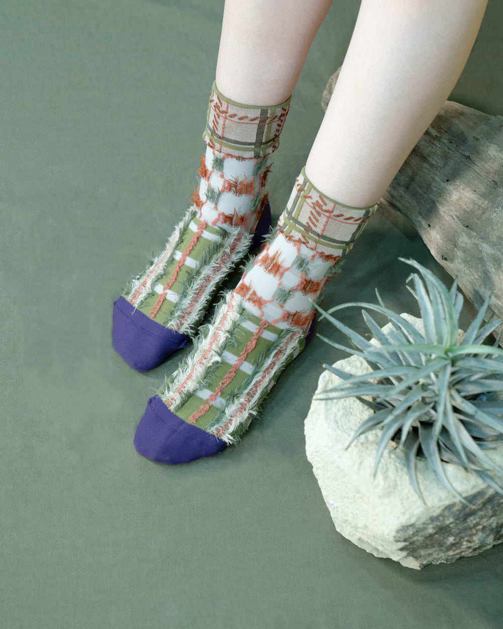 A model wearing Atelier Textiles socks in green, orange and purple, made in Japan, showcasing their unique patterns and versatility against a stylish outfit.