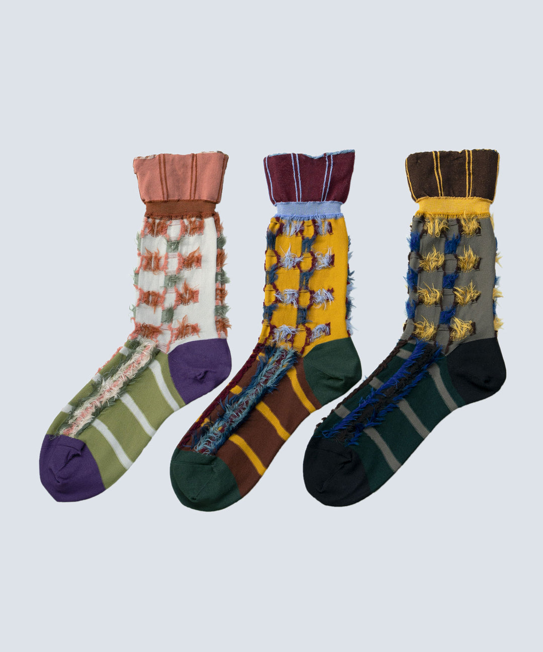 Image of three different styles of Atelier Textiles socks in pink, yellow, and charcoal grey, arranged together to showcase their front sides and unique patterns.