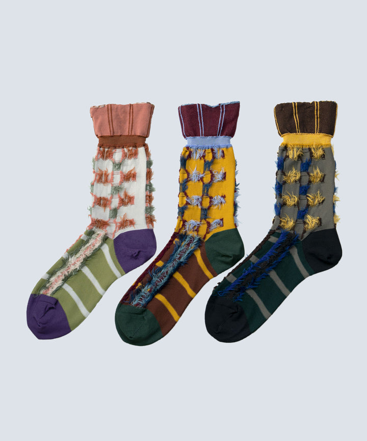 Image of three different styles of Atelier Textiles socks in pink, yellow, and charcoal grey, arranged together to showcase their front sides and unique patterns.