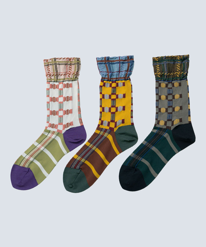Image of three different styles of Atelier Textiles socks in pink, yellow, and charcoal grey, arranged together to showcase their front sides and unique patterns.