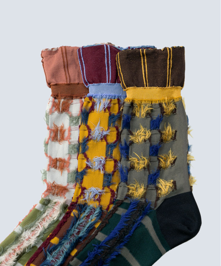 Close-up image of Atelier Textiles socks in pink, yellow, and charcoal grey, made in Japan, highlighting the fine details, textures, and patterns of each sock.