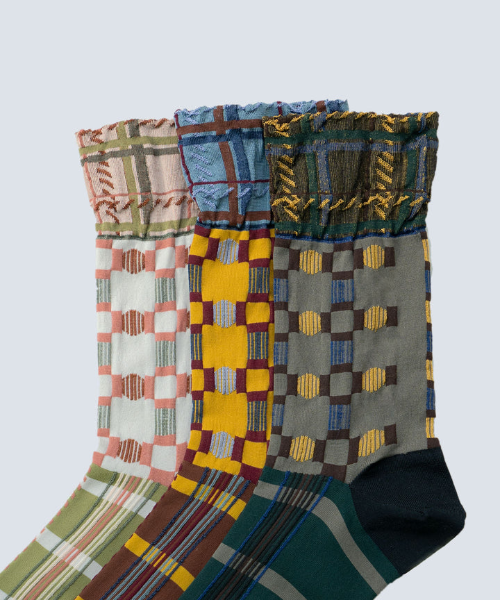 Close-up image of Atelier Textiles socks in pink, yellow, and charcoal grey, made in Japan, highlighting the fine details, textures, and patterns of each sock.