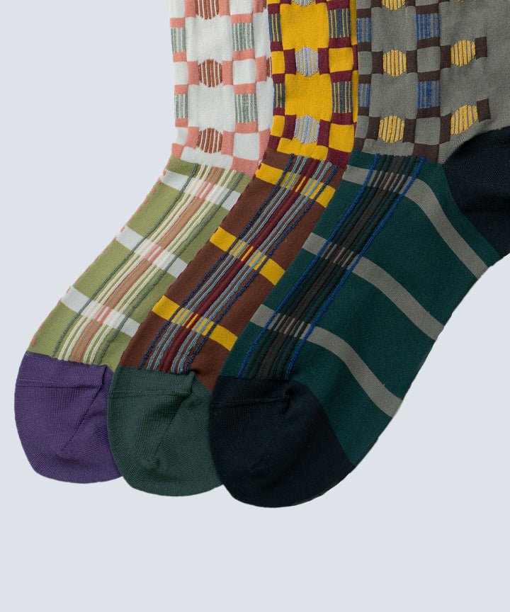 Close-up image of Atelier Textiles socks in pink, yellow, and charcoal grey, made in Japan, highlighting the fine details, textures, and patterns of each sock.