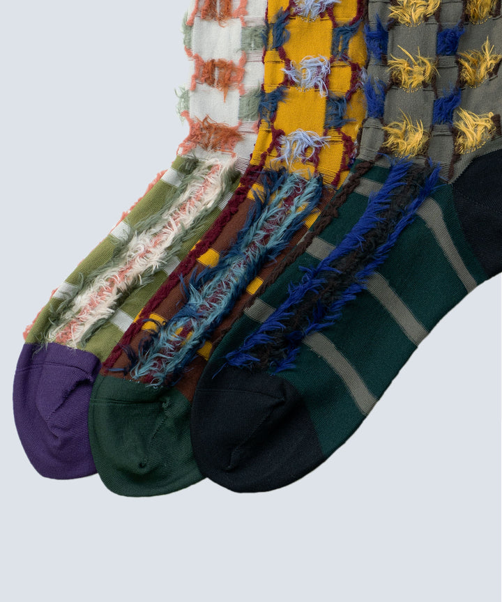 Close-up image of Atelier Textiles socks in pink, yellow, and charcoal grey, made in Japan, highlighting the fine details, textures, and patterns of each sock.