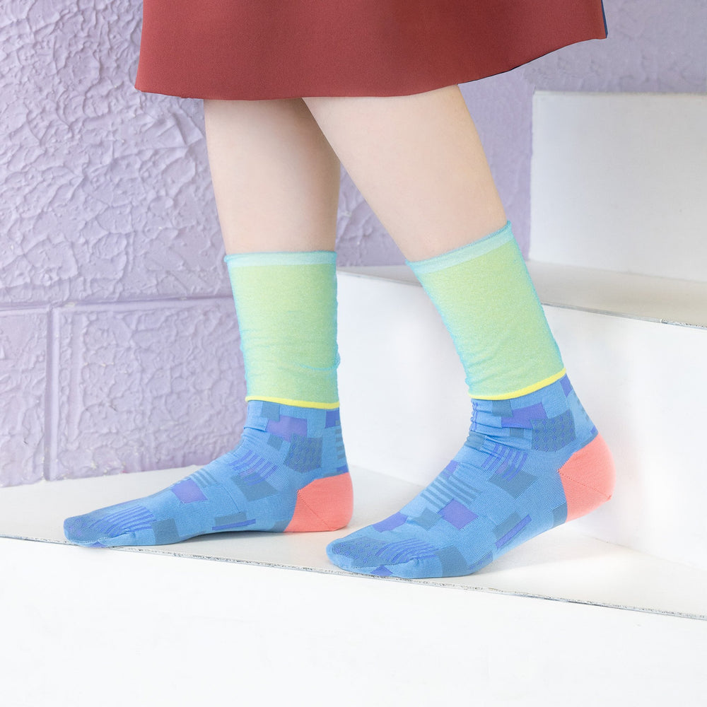 A model wearing COQ Sunlight Block Socks in blue, made in Japan, styled with a brown dress, showcasing the unique geometric patterns of the socks.