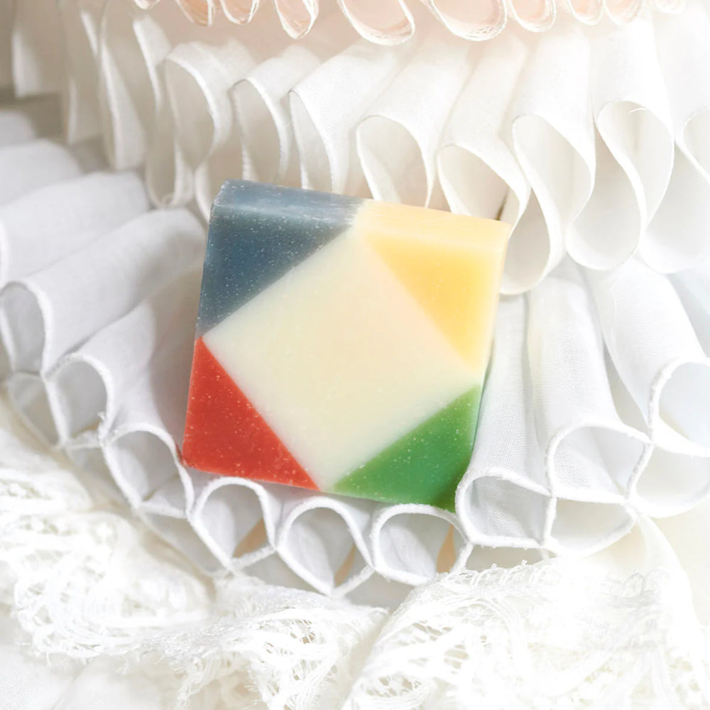 Colorful organic Ciment Arlequin Poudrée soap on a white backdrop.