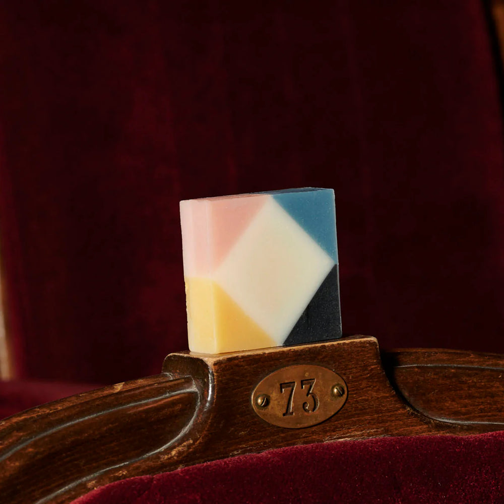 Colorful organic Ciment Arlequin rose soap placed on top of a chair in a theater.