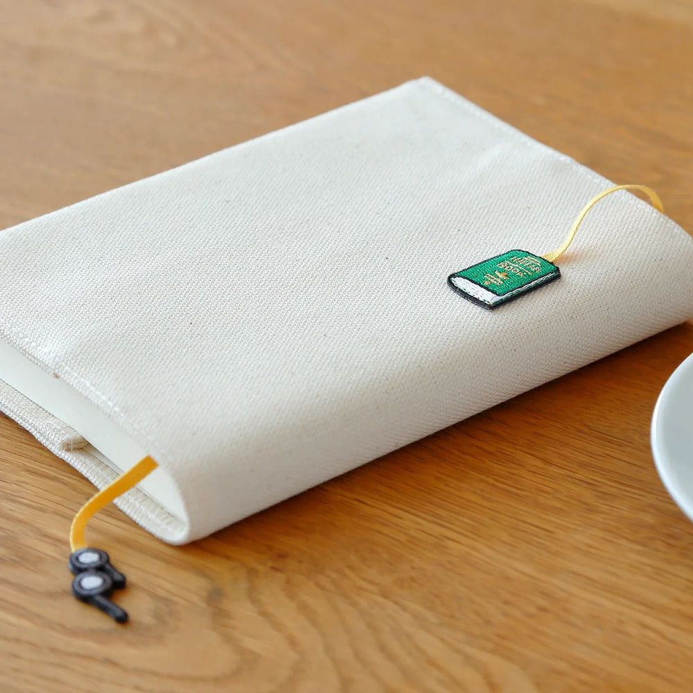 White pouch with a green bookmark on a wooden desk