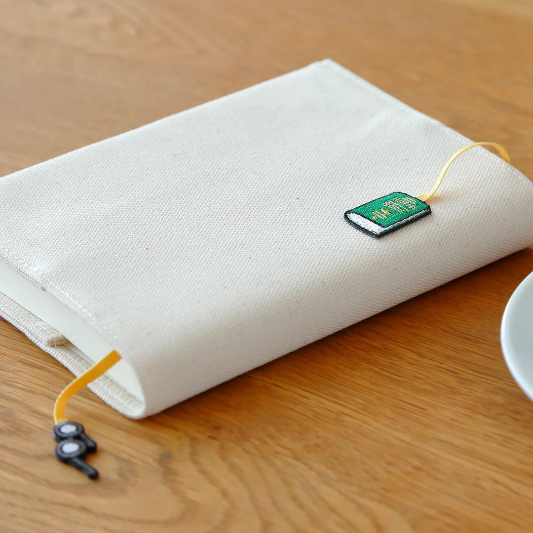 White pouch with a green bookmark on a wooden desk
