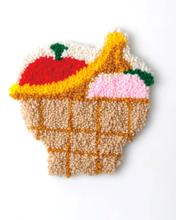 Decorative item resembling a waffle cone with ice cream and fruit on a white background