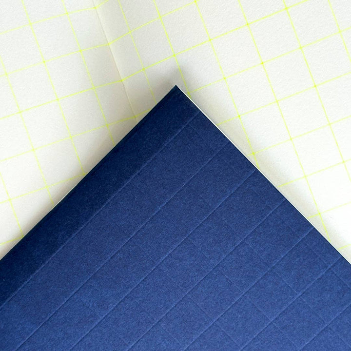 Blue notebook with textured surface on a white background with yellow grid lines