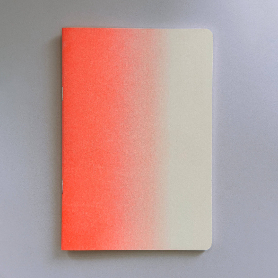 Notebook with a risograph gradient cover transitioning from red to beige on a gray background
