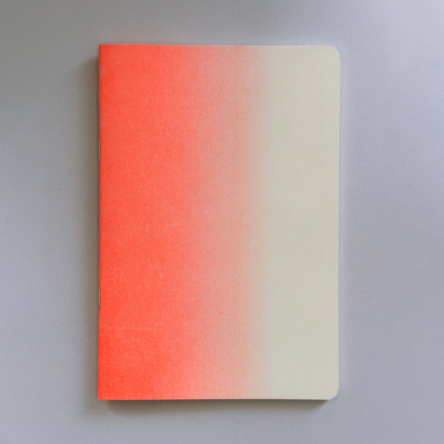 Notebook with a risograph gradient cover transitioning from red to beige on a gray background