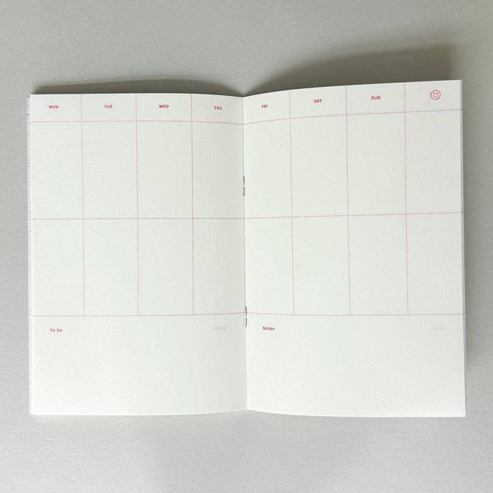 Open weekly planner with grid layout on a gray background