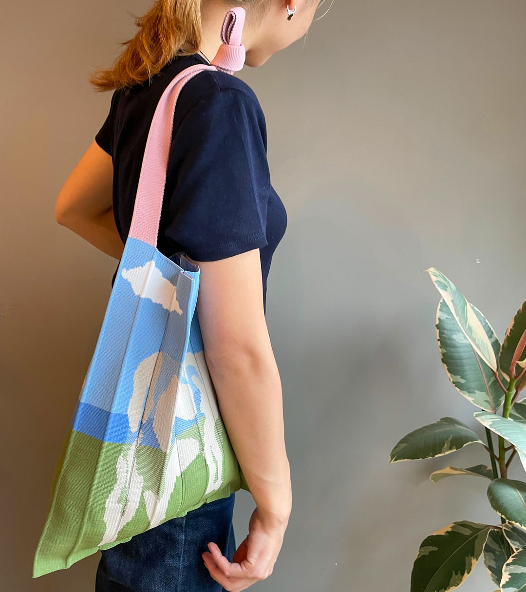 A model wearing the KNT 365 Knitty Tote Bag with a cow illustration over her shoulder, with the strap shortened a bit to match her blue T-shirt.