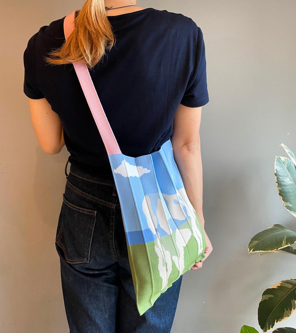 A model wearing the KNT 365 Knitty Tote Bag with a cow illustration diagonally over her shoulder, with the strap shortened slightly to match her blue T-shirt.