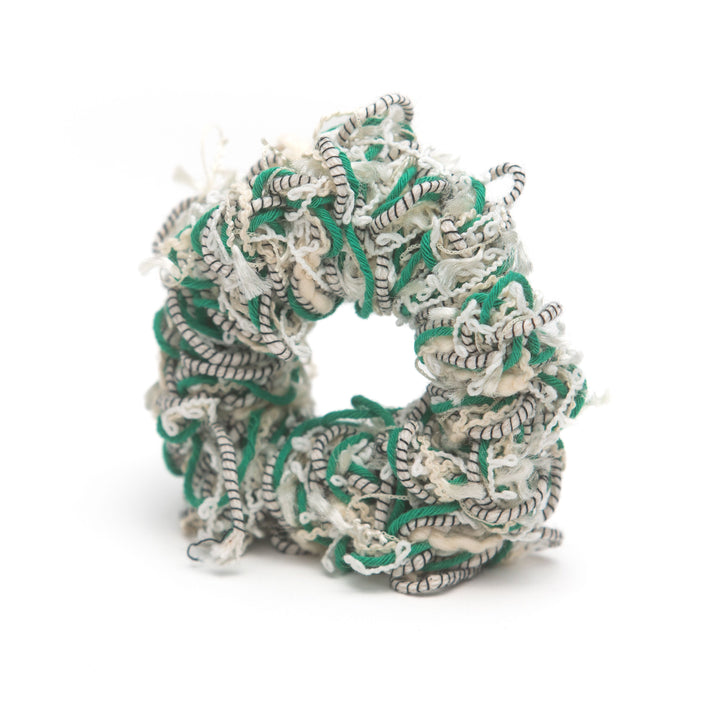 A handmade green and white striped crochet scrunchie, styled as a vibrant hair accessory.