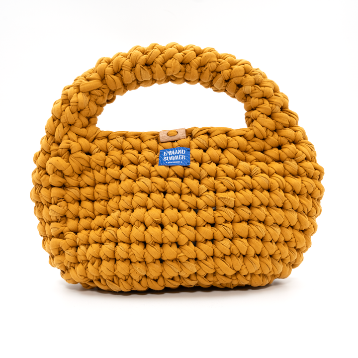 Yellow woven handbag with a visible brand label on a white background