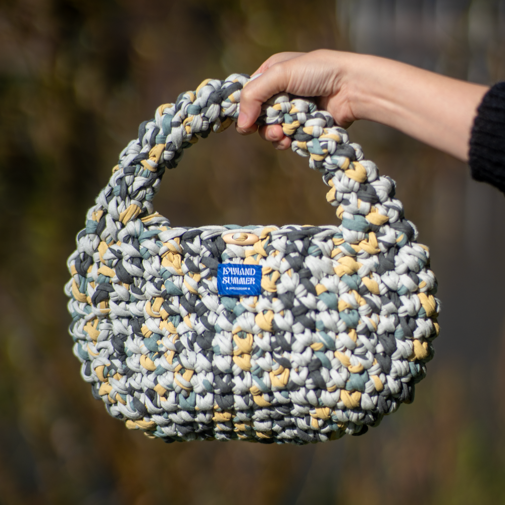 Handmade woven bag held by a person with a blurred natural background