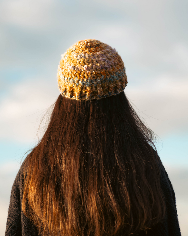 Person wearing a knitted beanie with a blurred natural background