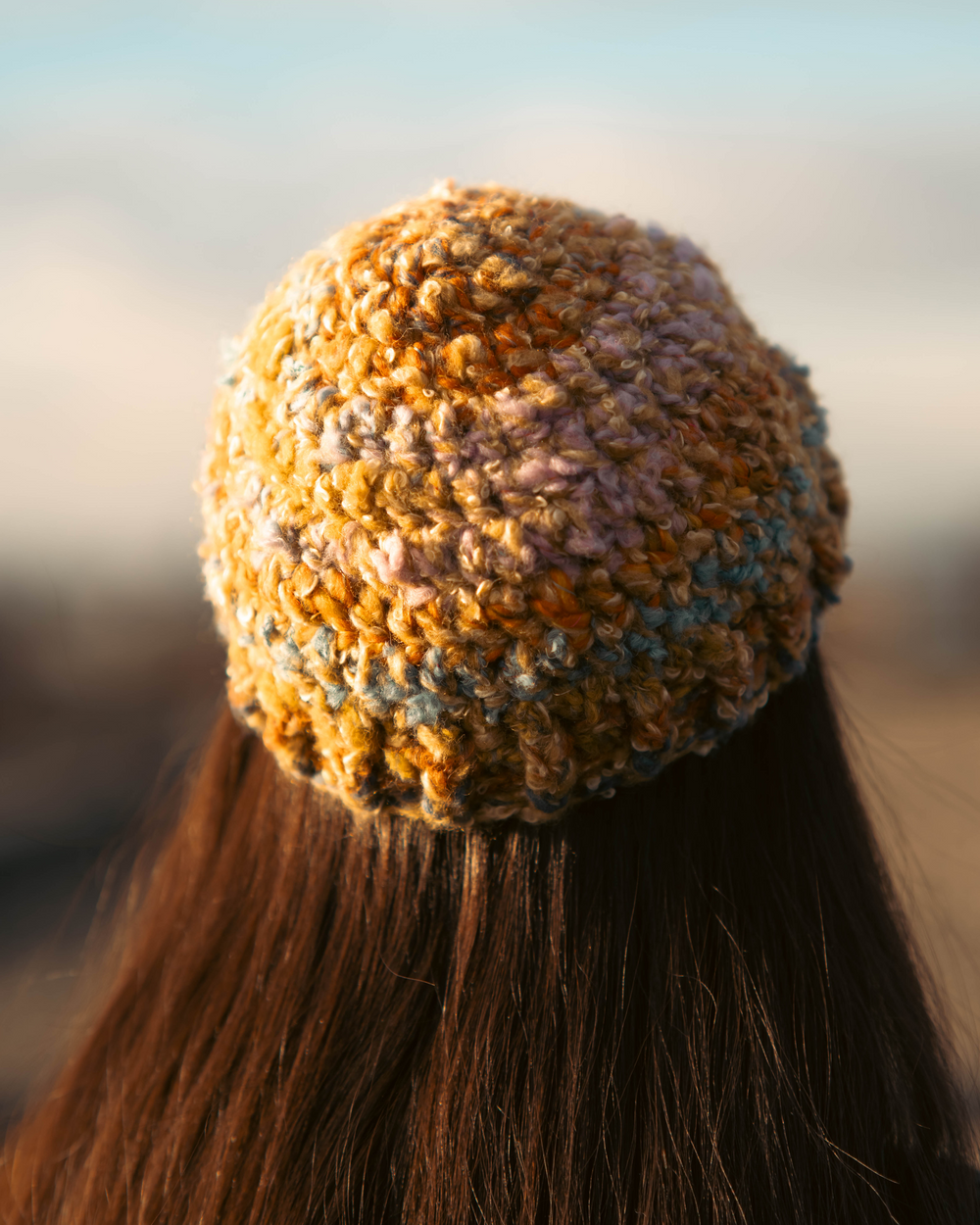 Person wearing a textured orange knit beanie with a blurred background