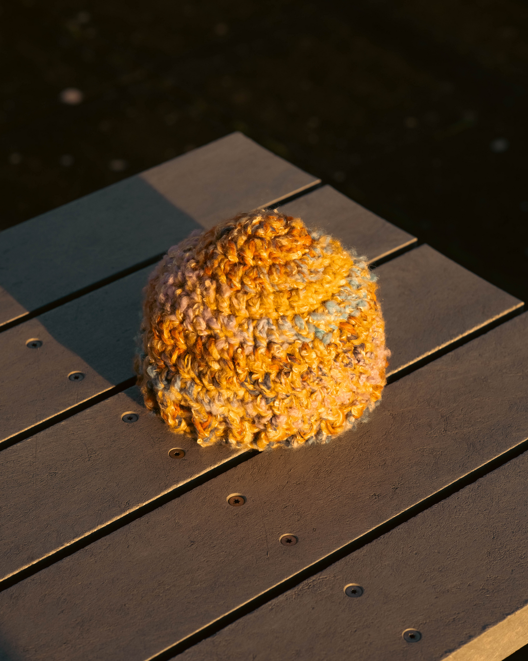 Orange knitted hat on a wooden surface with water in the background