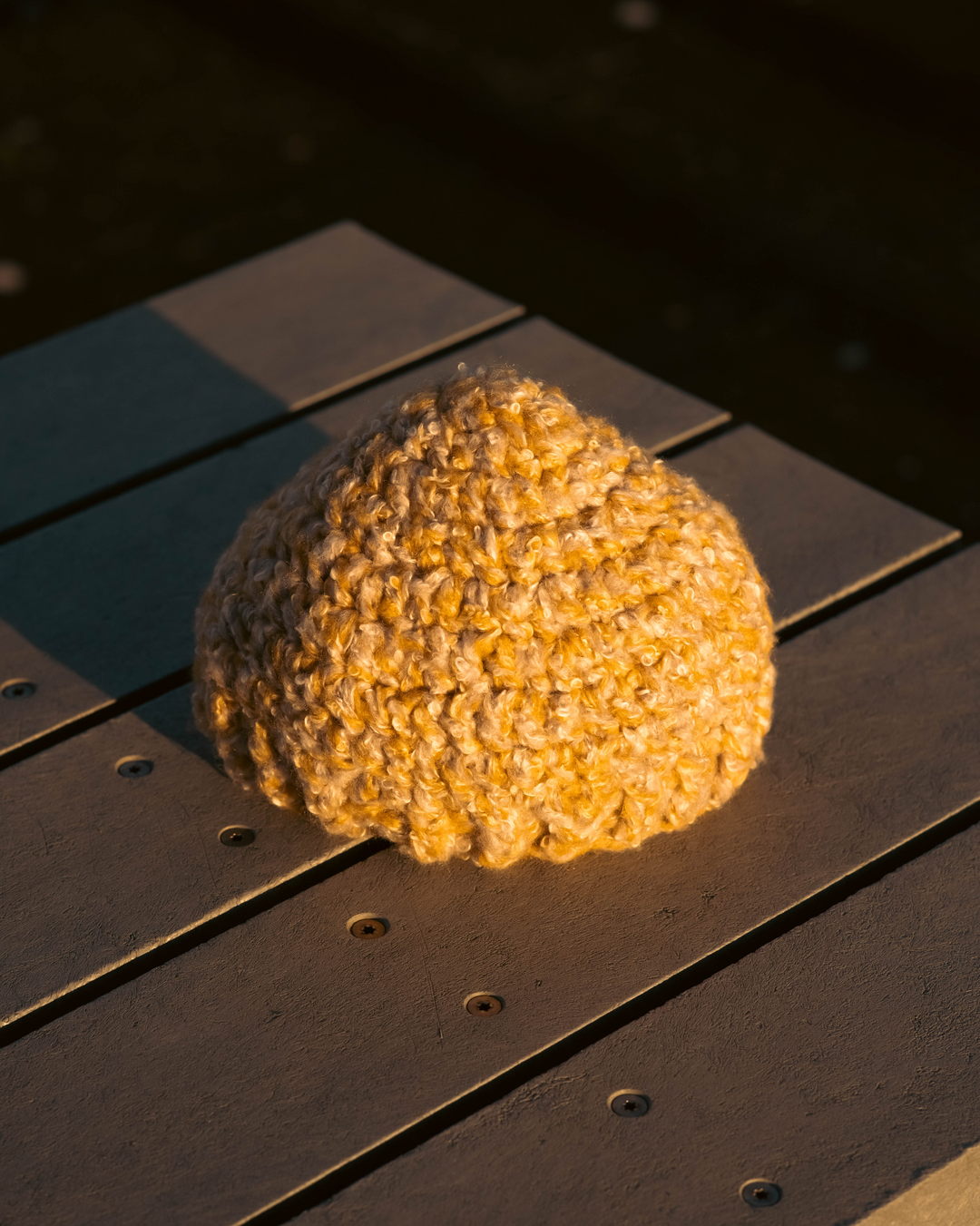 Textured yellow beanie on a dark wooden surface