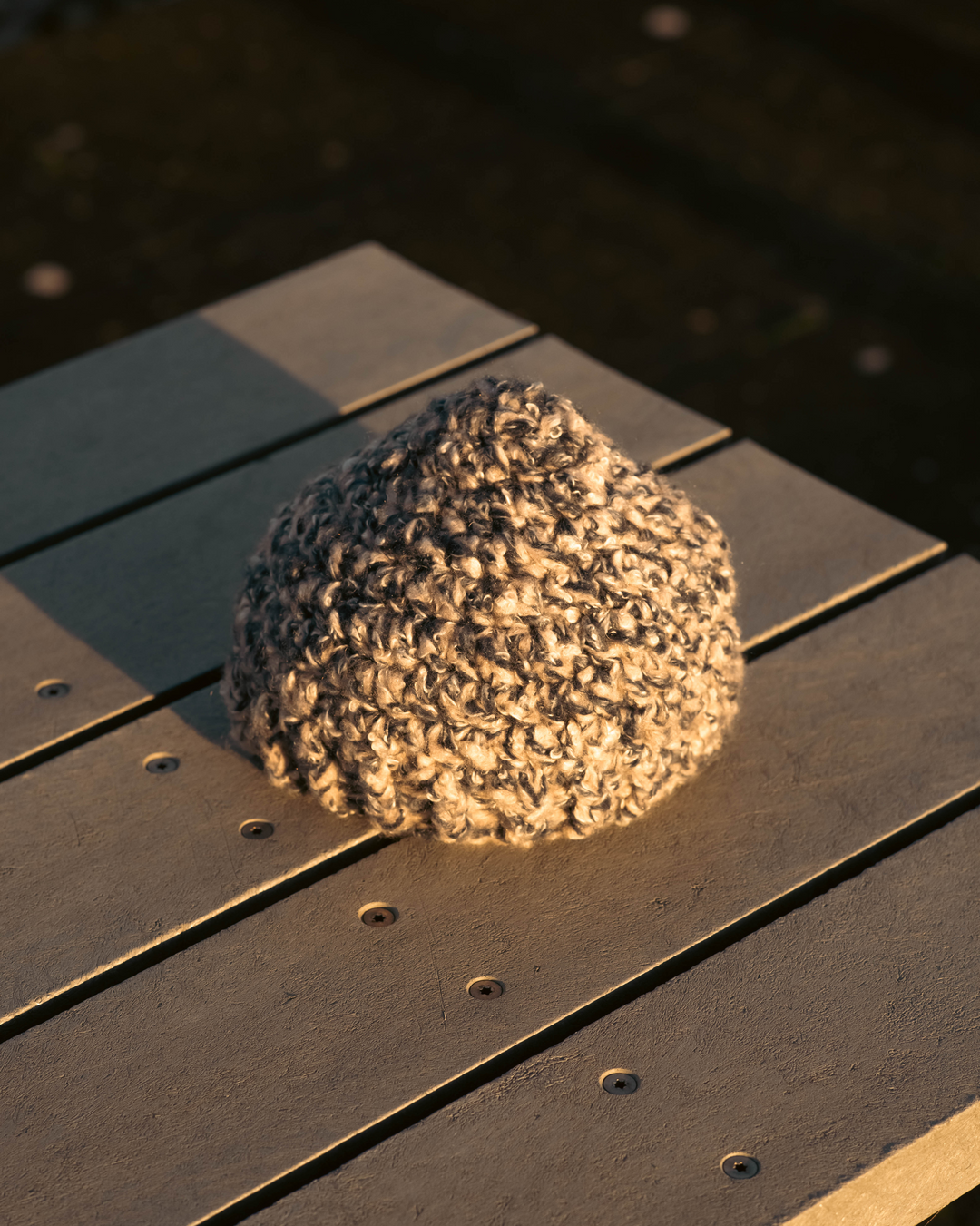 Blue and Grey knitted beanie on a wooden surface with a blurred background