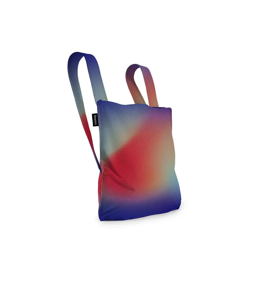 Image of a Notabag displayed in its backpack shape, designed to resemble an aurora with vibrant colours of red, purple, blue, and green, showcasing its versatility and unique design.