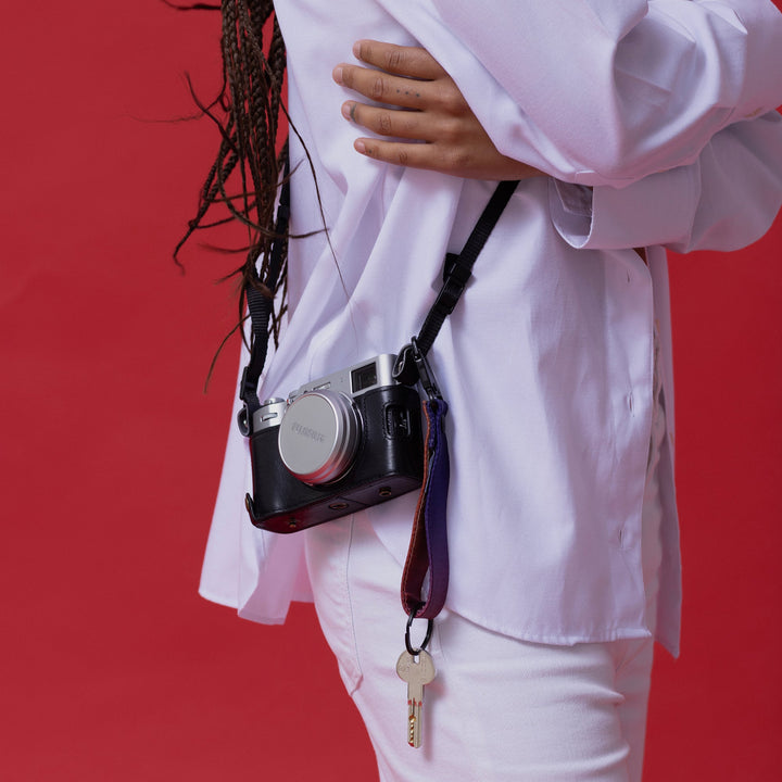 Person wearing a white lab coat with a camera around their neck against a red background