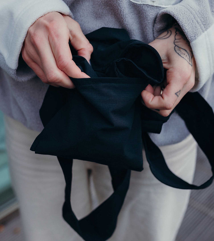 A model folding the black Notabag into a wallet-sized form, demonstrating how compact and handy it is for easy storage and transport.