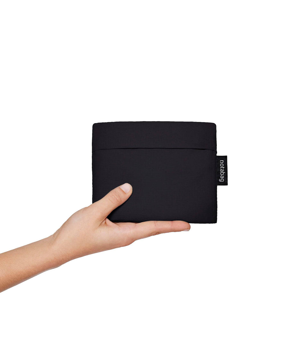 A model folding the black Notabag into a wallet-sized form, demonstrating how compact and handy it is for easy storage and transport.