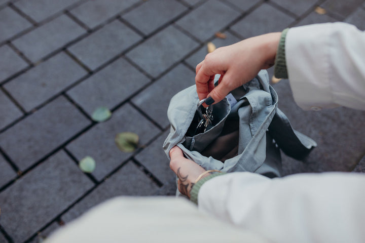 A model taking her keys out from the small inside pocket of the grey Notabag, demonstrating the bag's compartments for easy organization and access to different items.