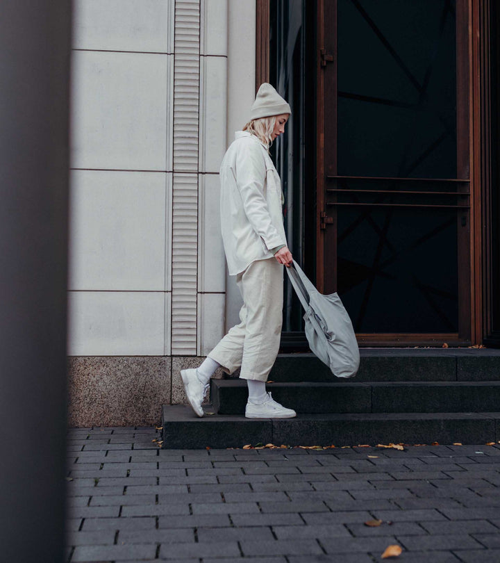 A model swinging the grey Notabag with her hand, demonstrating how lightweight and easy to carry the bag is.