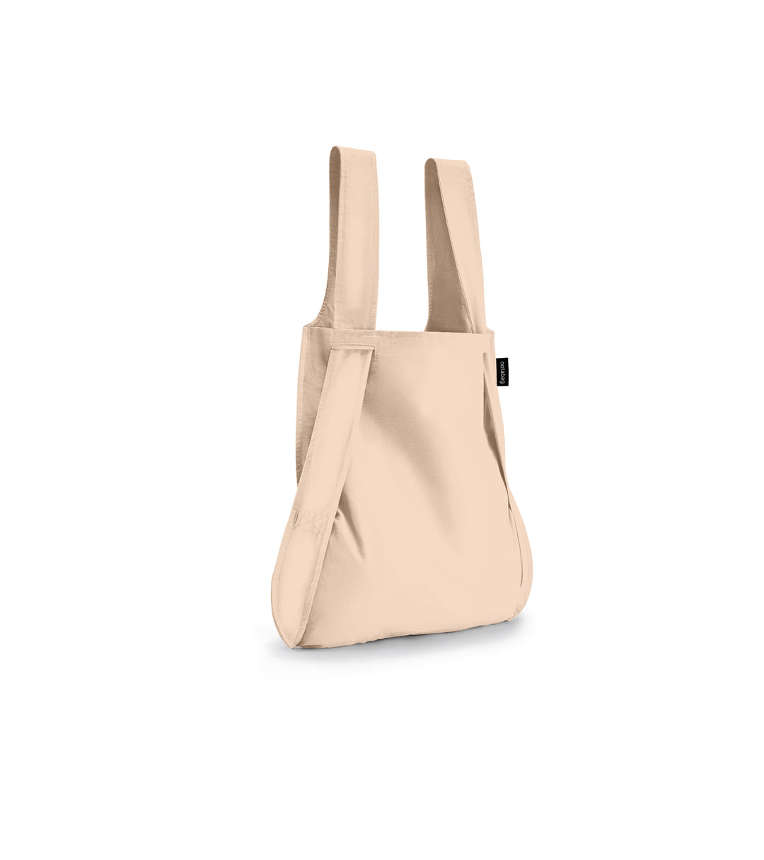 Image of a sand beige Notabag displayed in its backpack shape, showcasing its versatility and design.