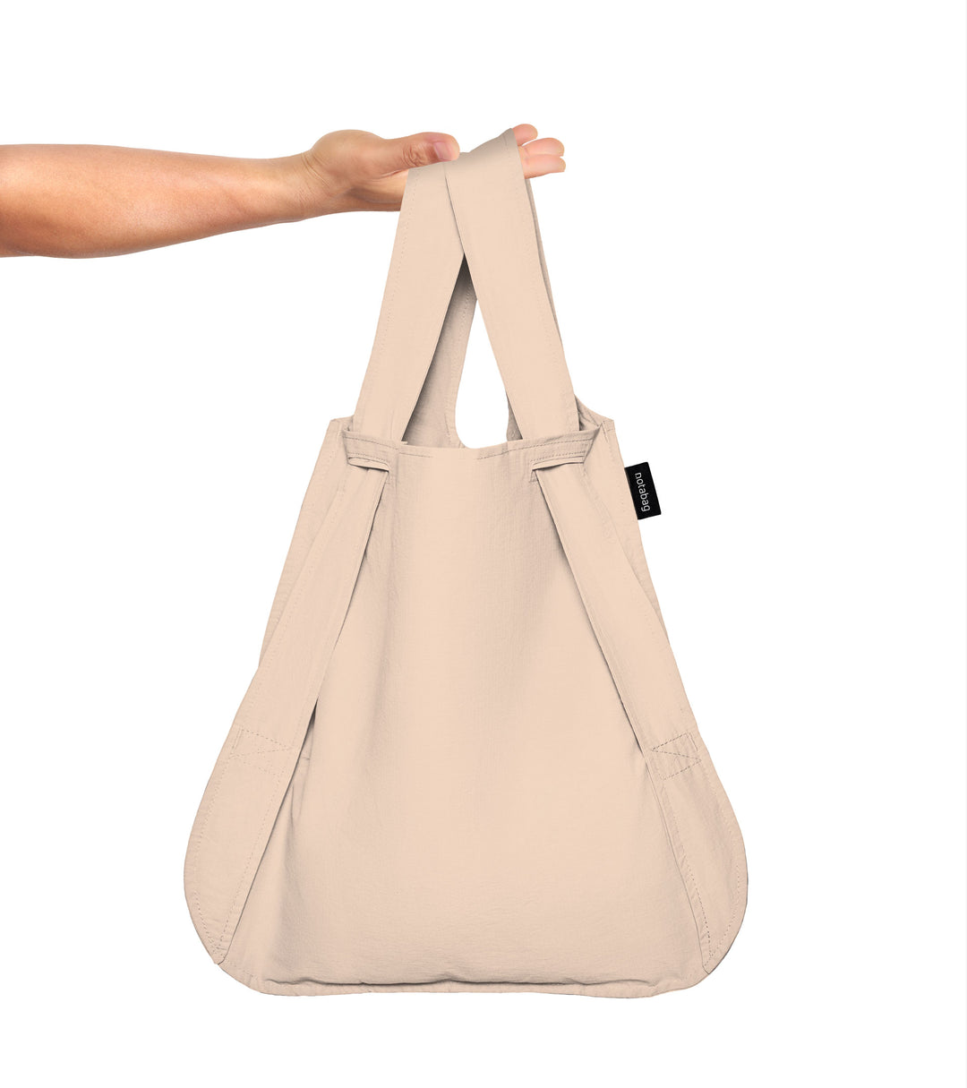 A model holding the sand beige Notabag in her hand, demonstrating its spacious size.