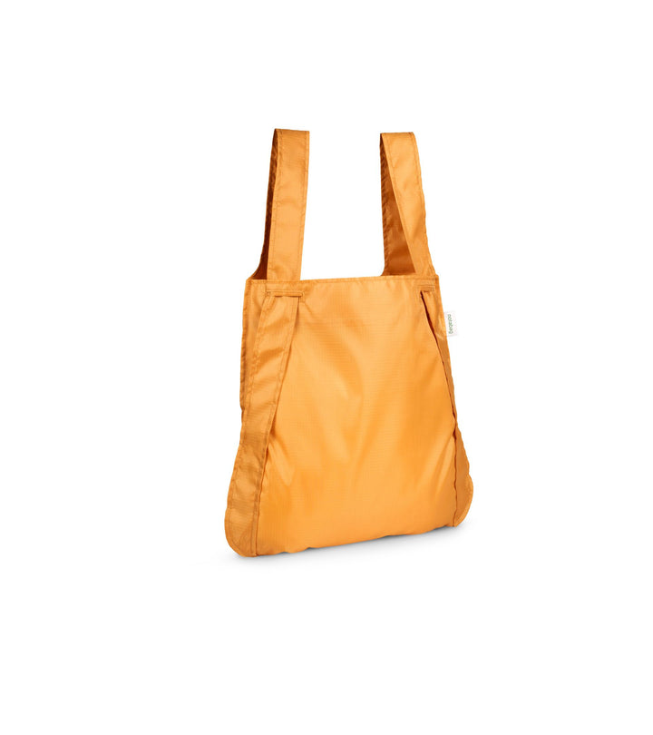 Image of a mustard orange Notabag displayed in its backpack shape, showcasing its versatility and design.