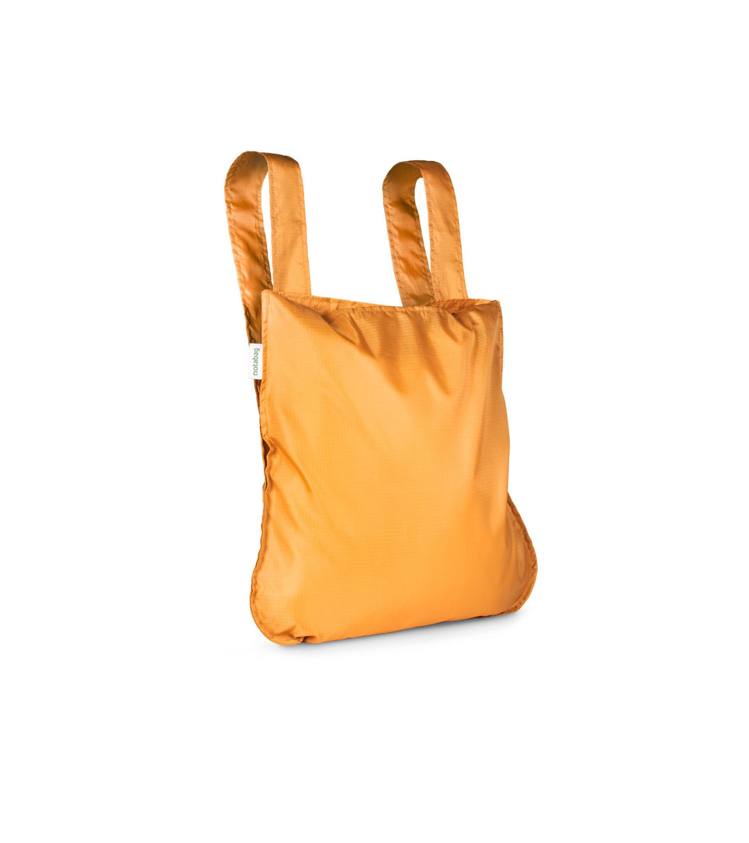 Image of a mustard orange Notabag displayed in its backpack shape, showcasing its versatility and design.