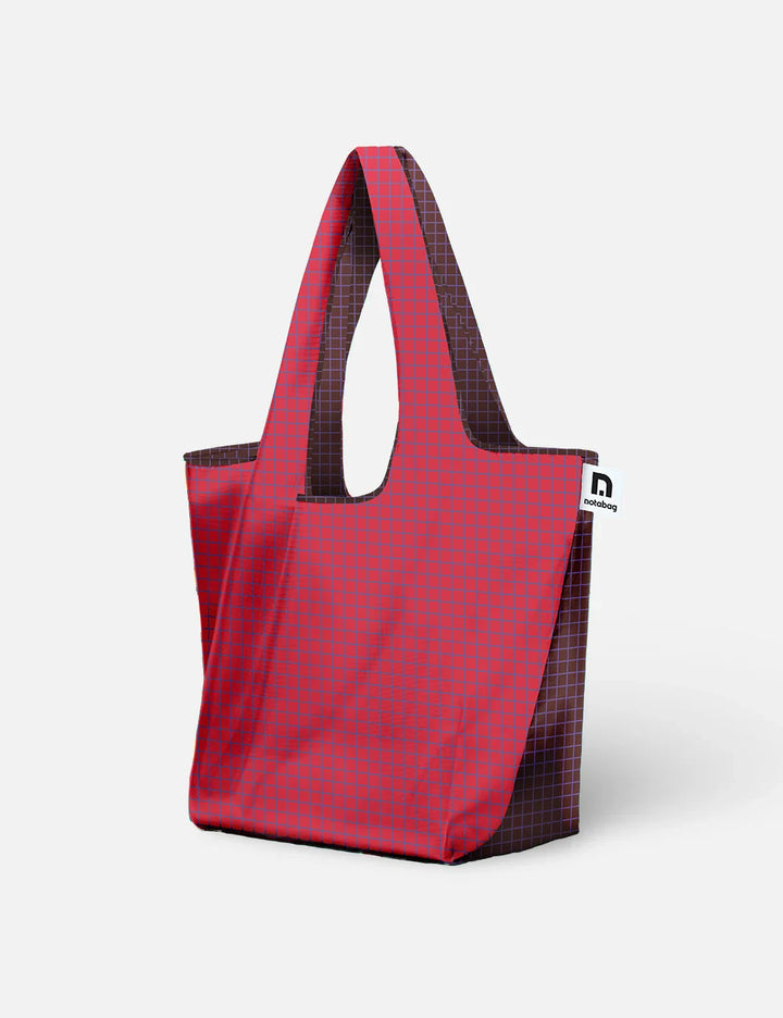 A red and purple plaid tote bag with dark brown handles and side panels, shown on a clean light grey background.