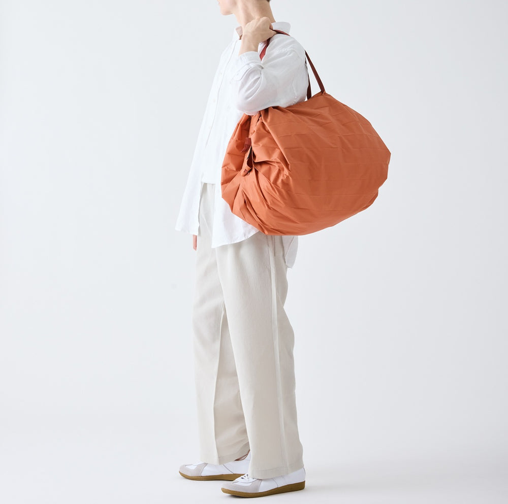 Person holding an orange bag against a white background