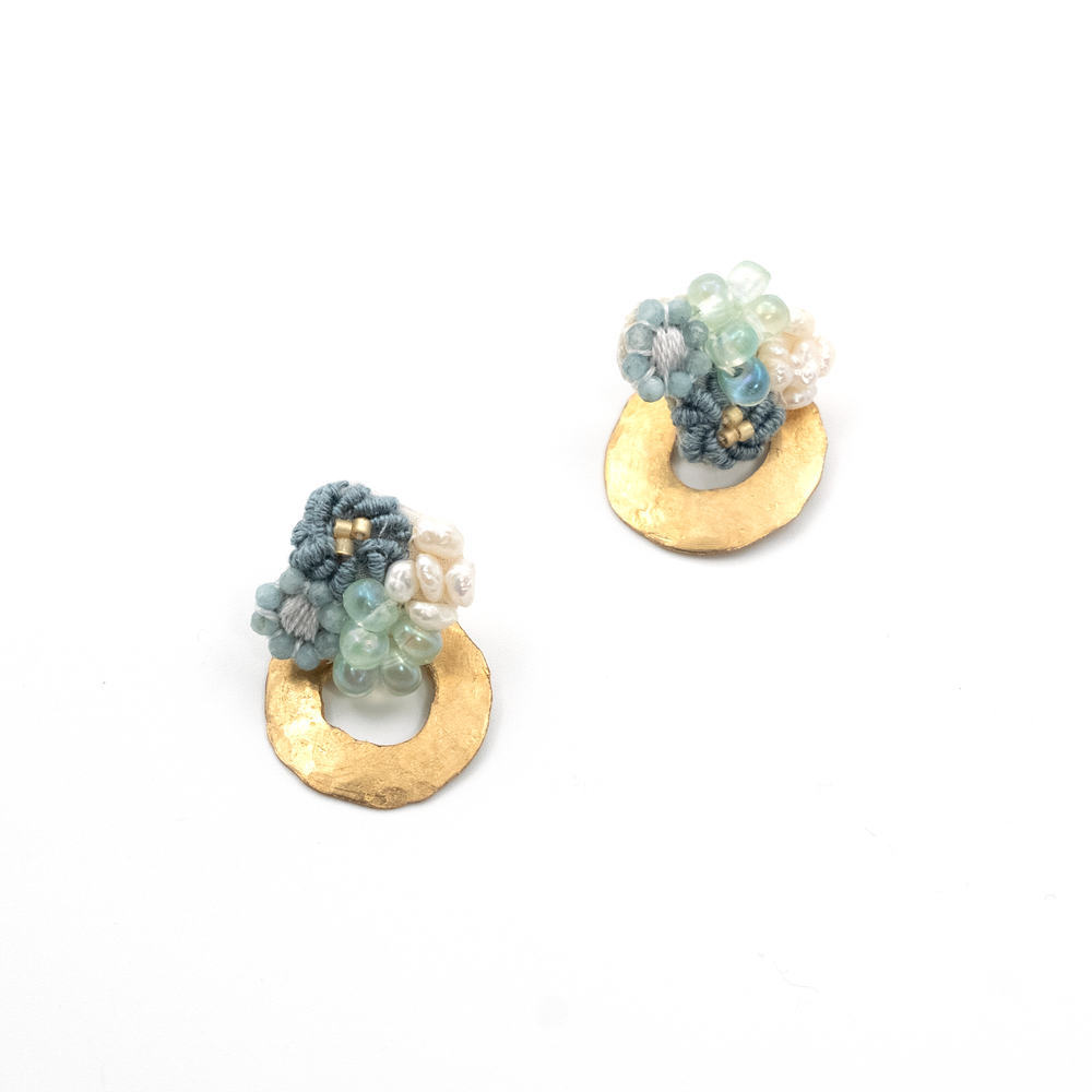 Pair of earrings with gold circular bases and floral designs on a white background