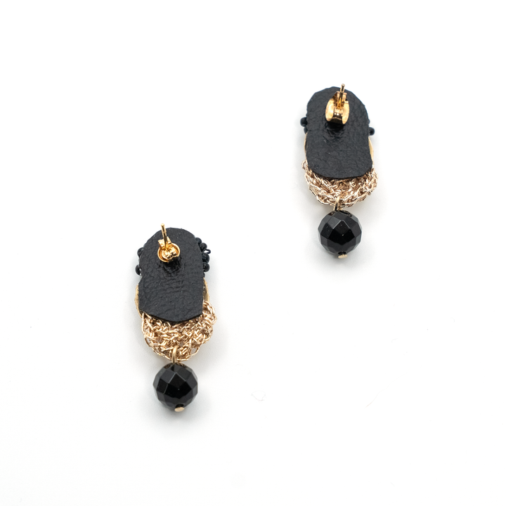 Pair of black and gold earrings on a white background