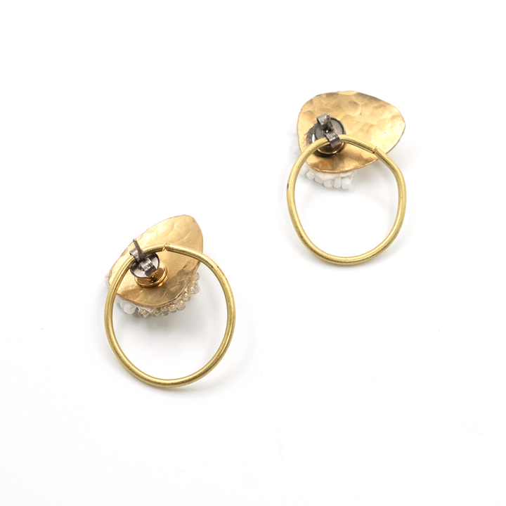 Gold hoop earrings with circular designs on a white background